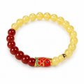 Beeswax amber and red agate beaded bracelet with a gold cloisonné koi fish charm, on white